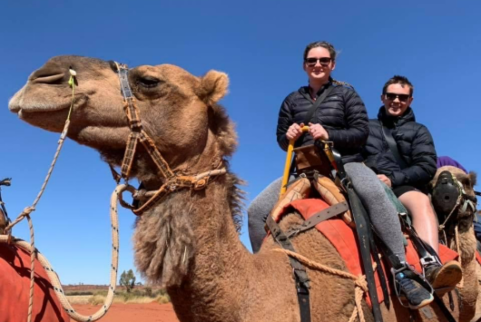 Luke & Catherine riding on camels wearing their macpac puffer jackets